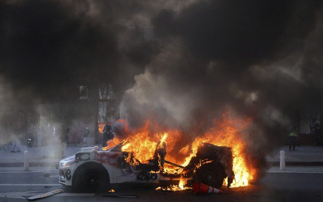 Sebuah mobil terbakar saat aksi protes menentang razia imigrasi federal di pusat kota Los Angeles, California, AS, Minggu (8/6/2025). Foto: Daniel Cole/REUTERS