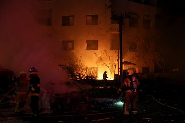 Petugas pemadam kebakaran bekerja di lokasi kejadian setelah serangan rudal dari Iran di Tel Aviv, Israel, Minggu (15/6/2025). Foto: Ronen Zvulun/REUTERS